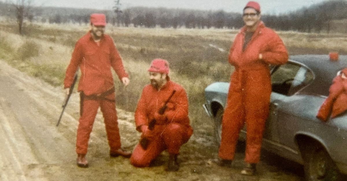Three deer hunters wearing orange posing in a cornfield