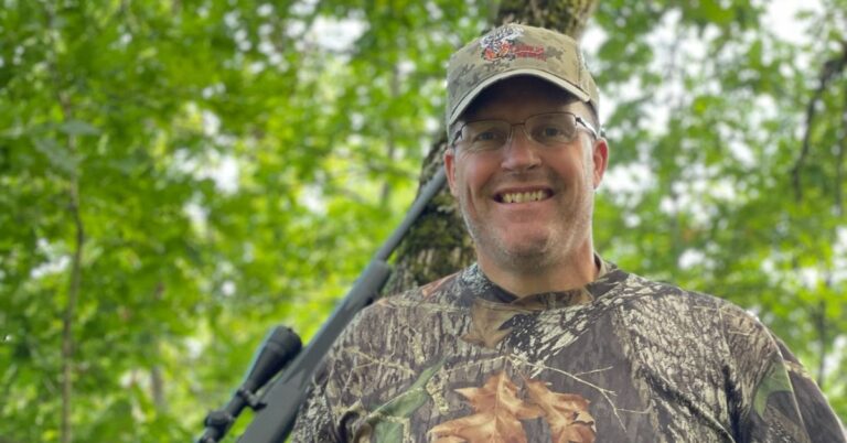Scott portrait standing in the woods by a tree. Get started hunting.
