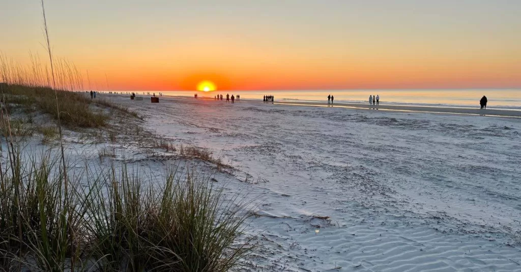 Small groups of people watching sunrise on the beach