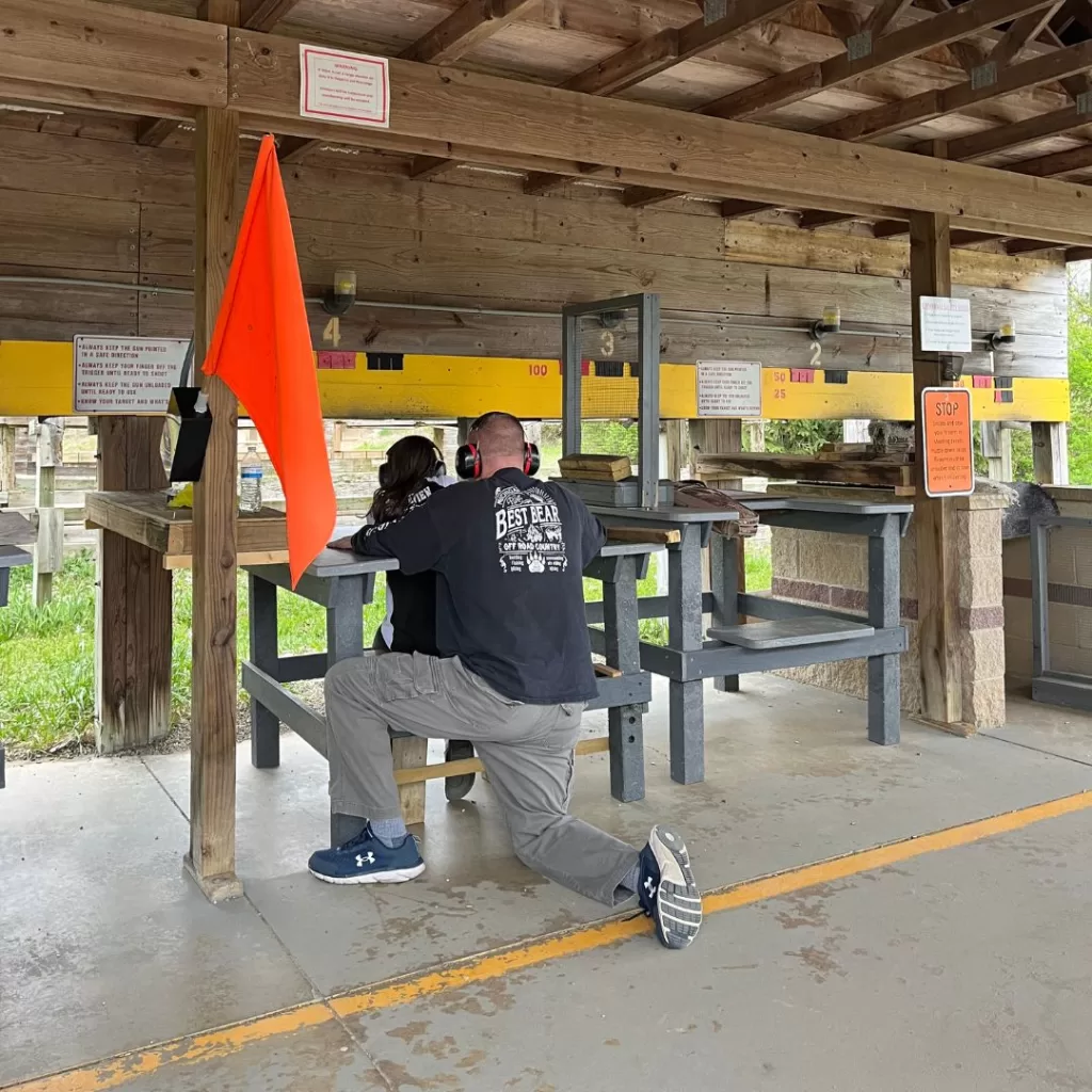 Hunting mentor showing youth hunter how to shoot a rifle in a firing stall