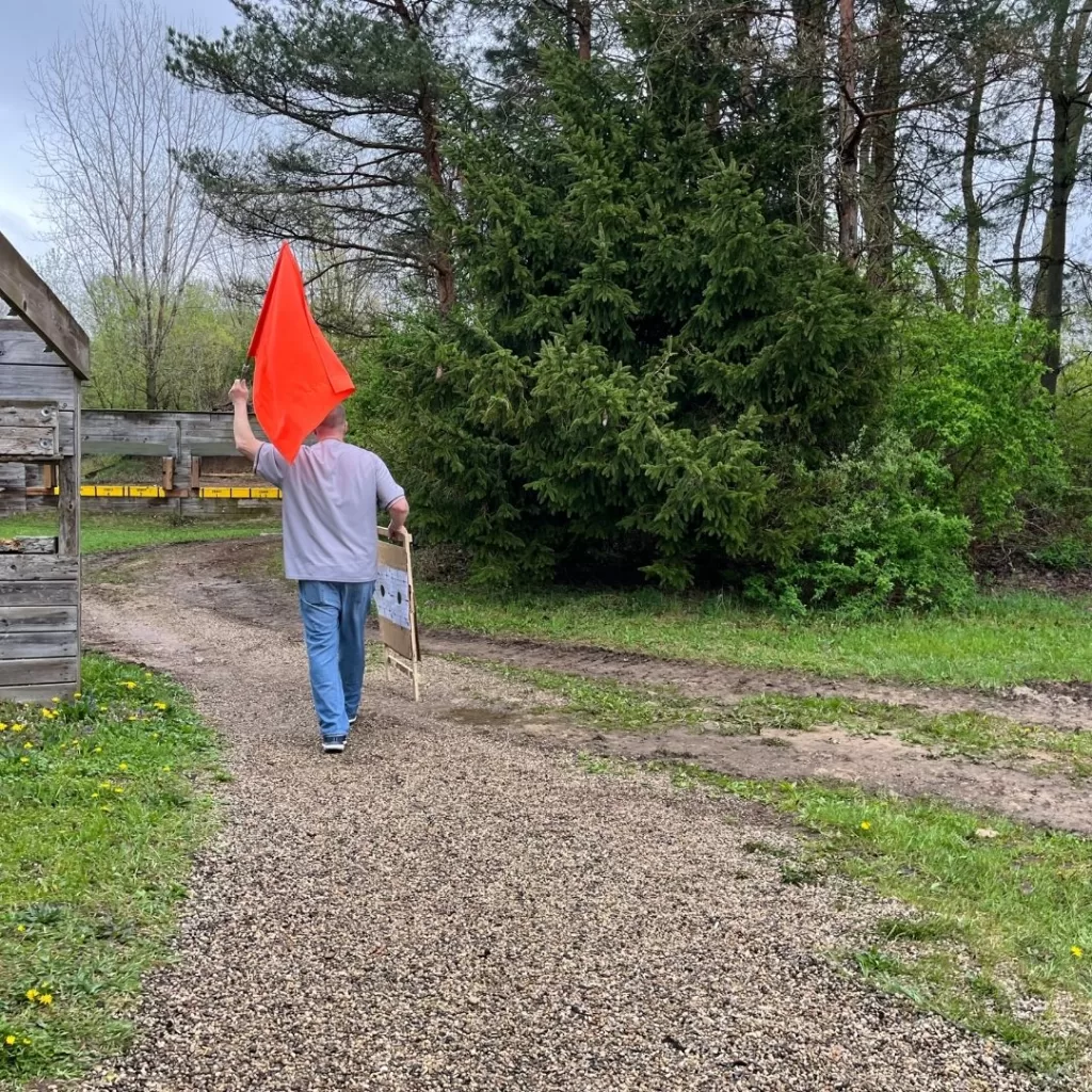 Experienced hunter walks downrange with the orange safety flag and target