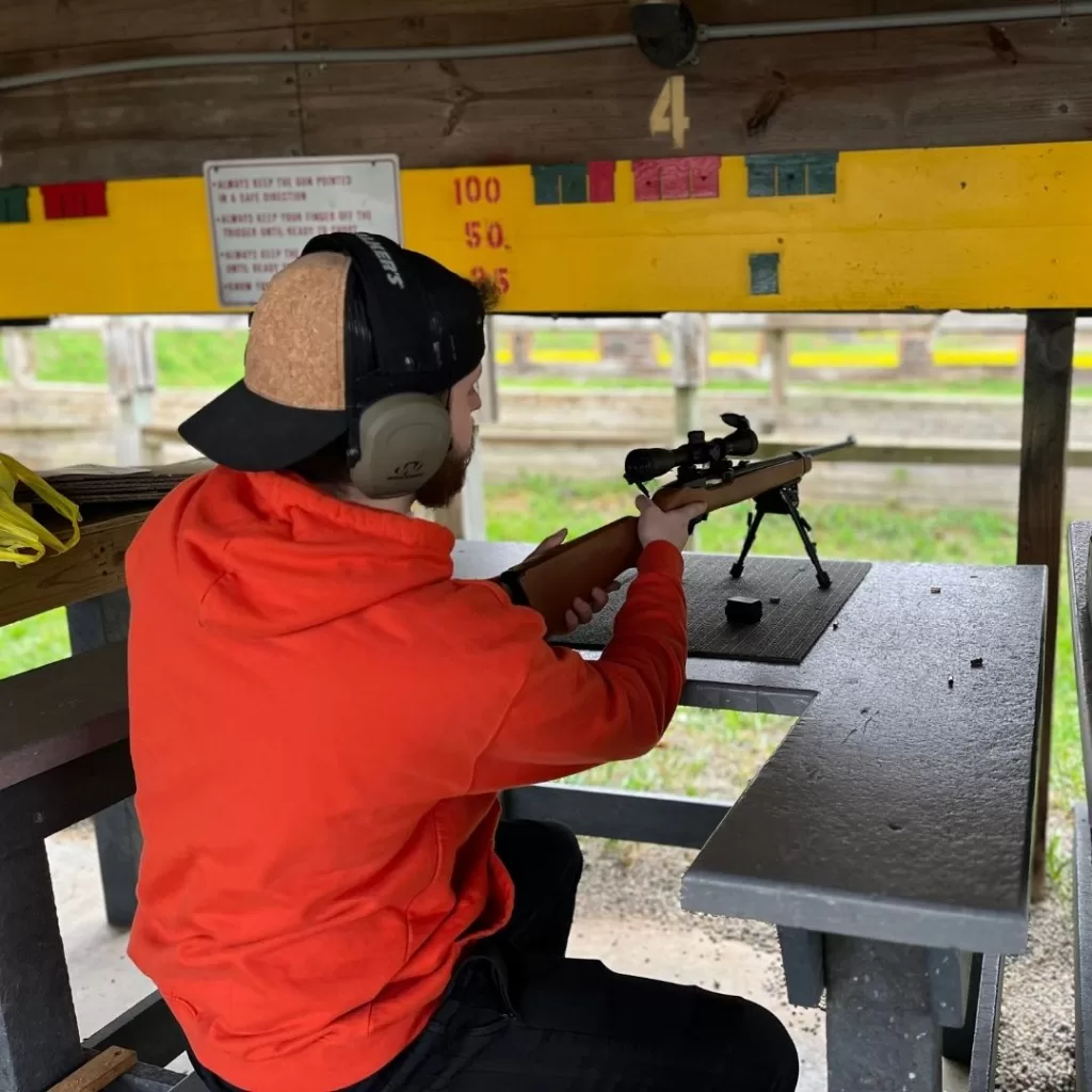 Young hunter gets ready to shoot a .22 rifle in a firing lane at a gun range.
