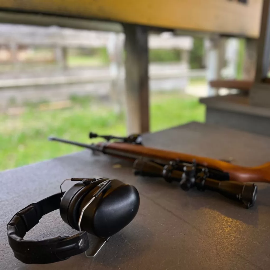 Ear muffs and rifle lay on a table at the gun range.