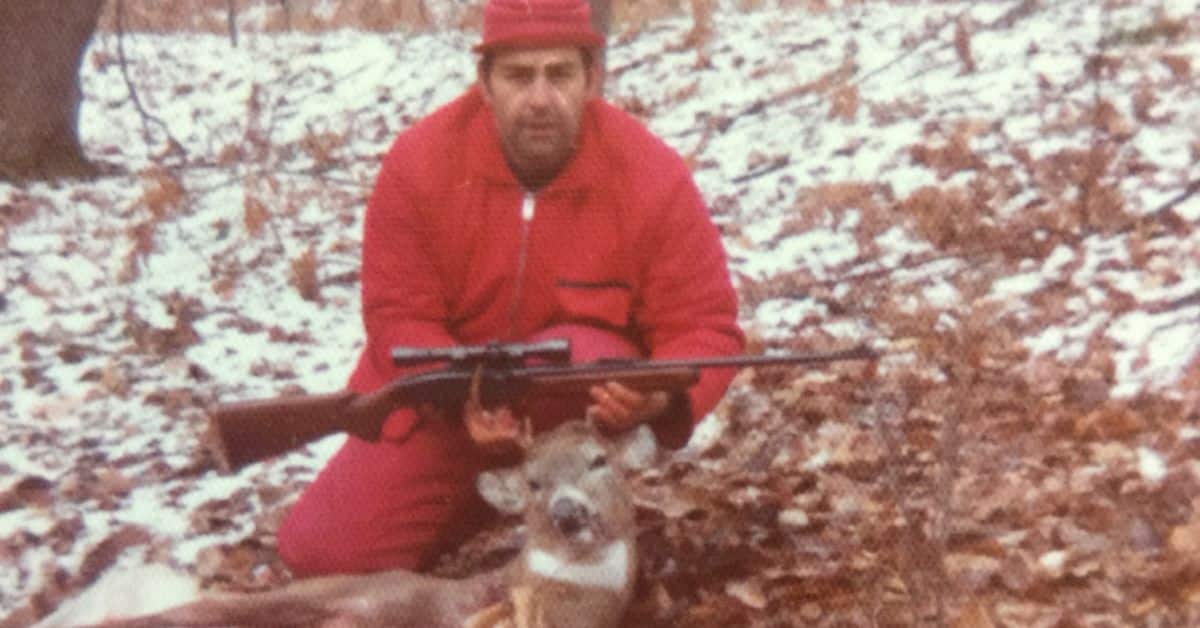 Hunter in orange with his deer and rifle.