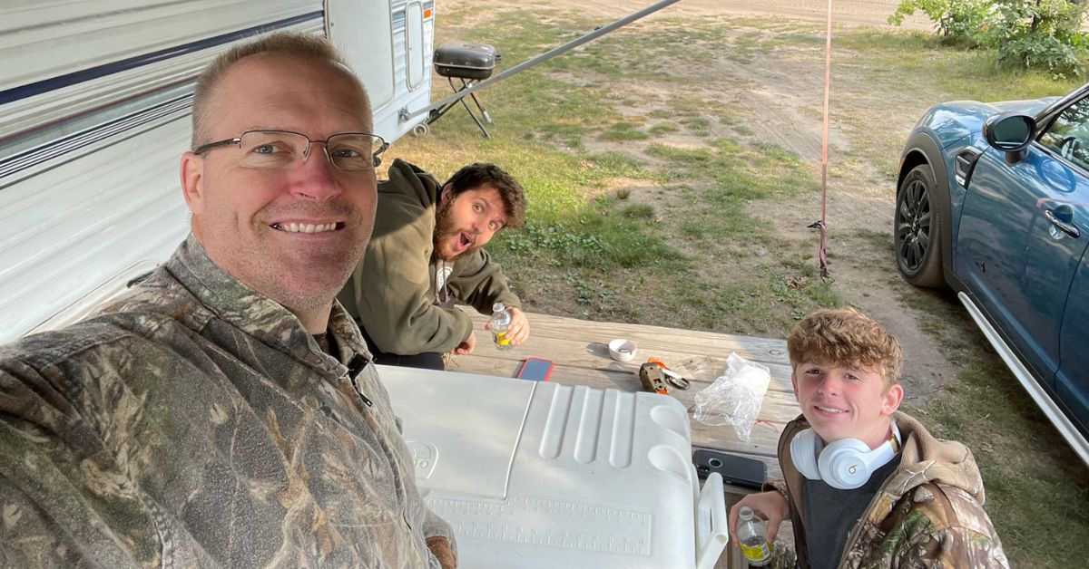 Three hunters hanging out at a picnic table on their hunting trip