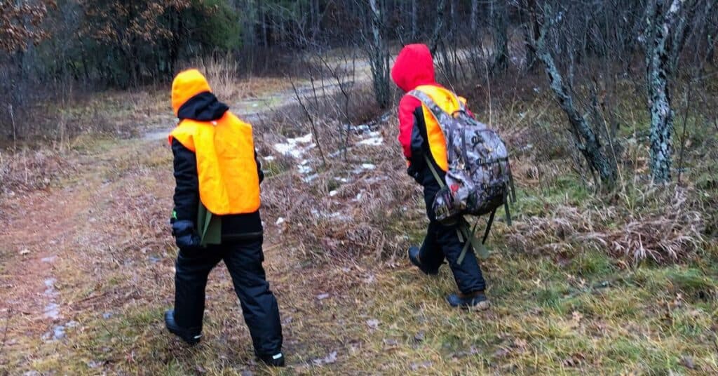 Two young hunters walking into the woods carrying a hunting backpack