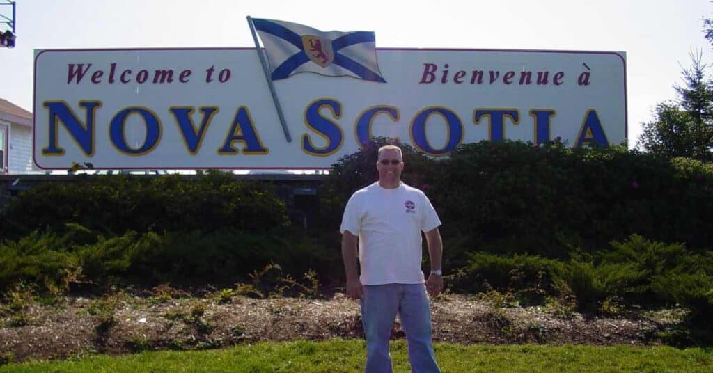 Scott standing in front of sign that reads Nova Scotia