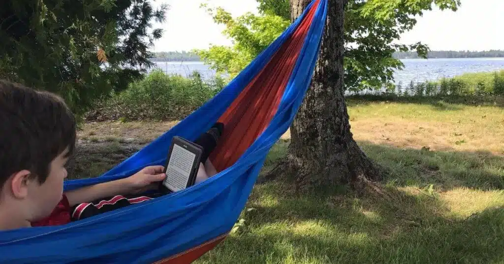 Boy in a hammock reading on a kindle
