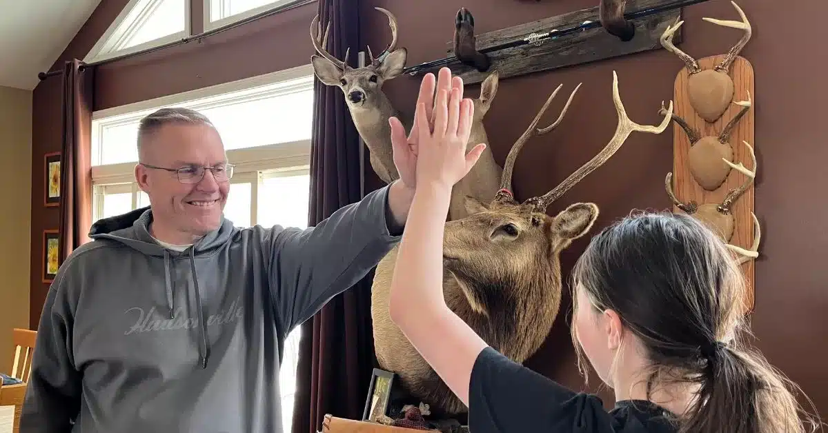 Two people give each other a high five with mounted taxidermy in the background