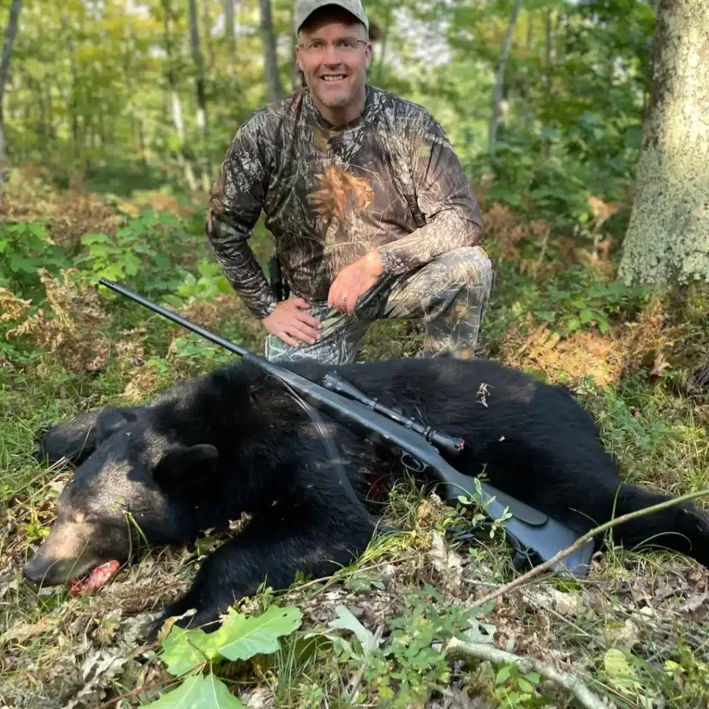 Hunter with Michigan Black bear and a rifle