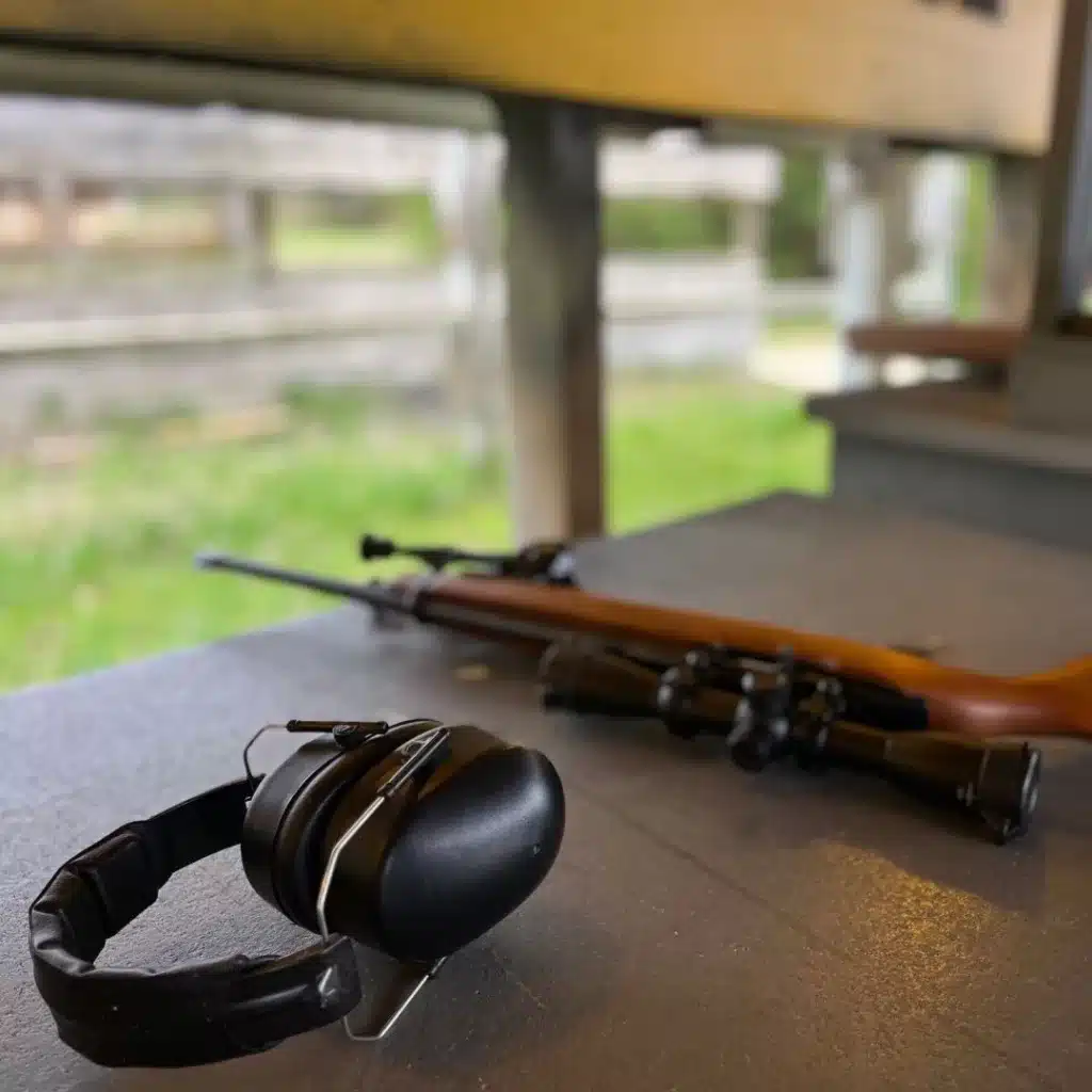 Ear muffs and rifle lay on a table at the gun range.