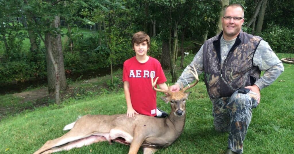 Two hunters posing by a whitetail deer buck in Michigan