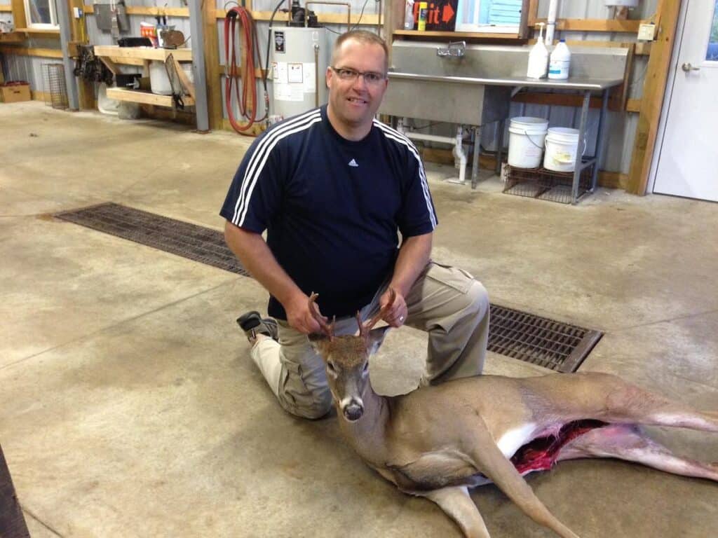 Hunter with harvested deer laying on ground