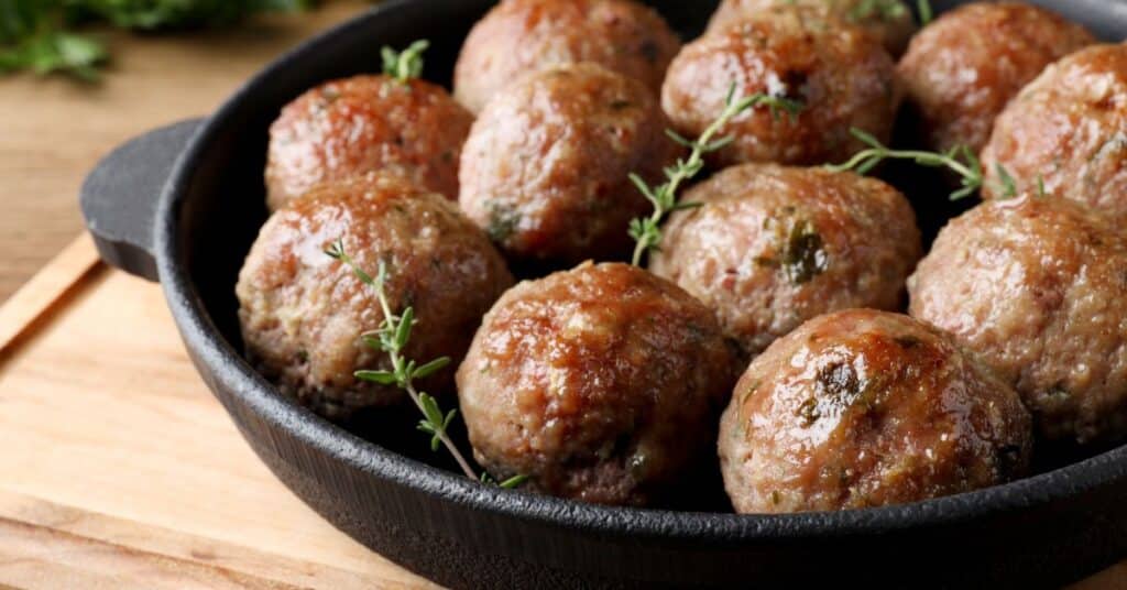 Several ground turkey meatballs in a black iron skillet and 5 simple ingredients