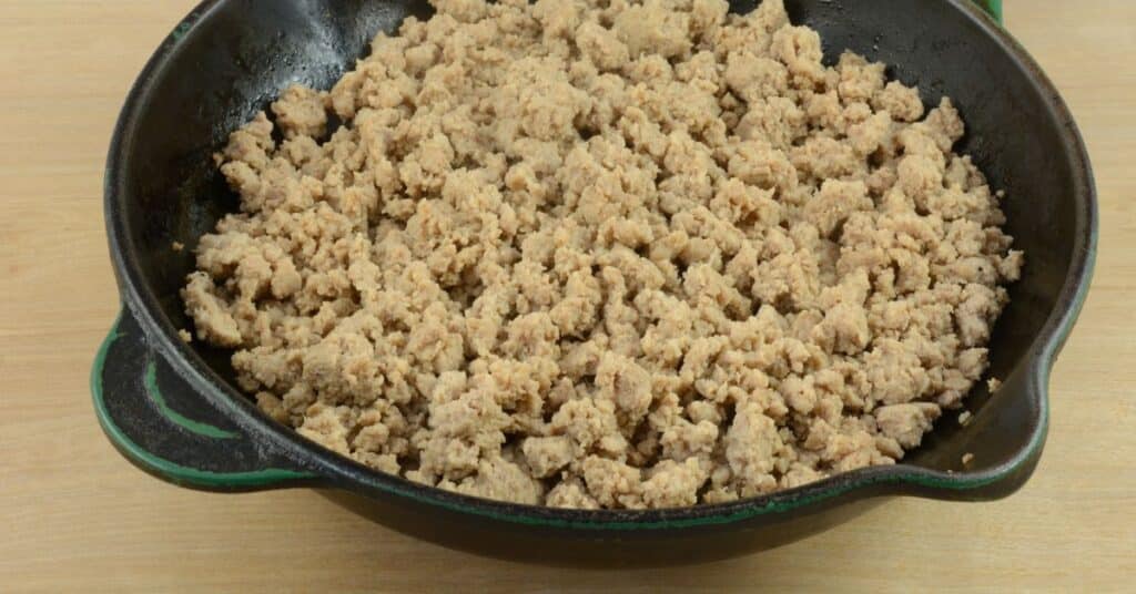 Ground turkey meat after being browned sitting in a black iron skillet
