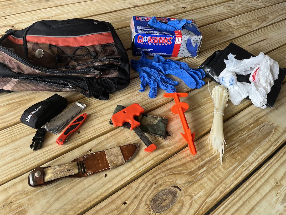 Knives, tools, bags and essentials display on a wood background