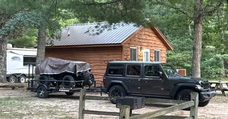 Rental cabin with a Jeep, utility trailer, and 4-wheeler parked in front, ready for early antlerless deer season